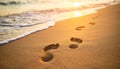 Footprints in sand with approaching waves at sunset Royalty Free Stock Photo