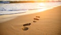 Footprints in sand with approaching waves at sunset Royalty Free Stock Photo