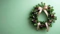 Tiny Christmas wreath with ribbon on matte pale green gradient Royalty Free Stock Photo