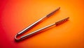 Single pair of metal barbecue tongs on matte gradient background from warm orange to soft red minimal composition Royalty Free Stock Photo