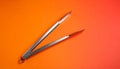 Single pair of metal barbecue tongs on matte gradient background from warm orange to soft red minimal composition Royalty Free Stock Photo