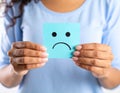 Woman holding sticky note with drawn sad face and suffering from cystitis on white Royalty Free Stock Photo