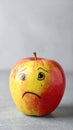 Apple with crying face on grey table, closeup. Concept of jealousy Royalty Free Stock Photo