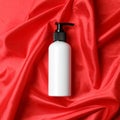 Bottle of hair care cosmetic product on red fabric, top view Royalty Free Stock Photo