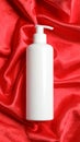 Bottle of hair care cosmetic product on red fabric, top view Royalty Free Stock Photo
