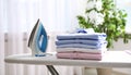 Neatly stacked freshly ironed shirts on ironing board in bright airy room Royalty Free Stock Photo