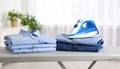 Neatly stacked freshly ironed shirts on ironing board in bright airy room Royalty Free Stock Photo