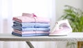 Neatly stacked freshly ironed shirts on ironing board in bright airy room Royalty Free Stock Photo