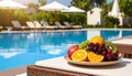 Plate with fresh fruits on table near sun lounger, space for text. Luxury resort Royalty Free Stock Photo