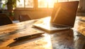 Wooden desk with laptop and pen, afternoon sun streaming in, subtle reflections Royalty Free Stock Photo