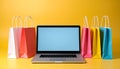 Online shopping. Laptop computer and colored paper bags on a yellow background Royalty Free Stock Photo