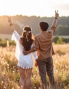 Hippie friends showing peace signs in field, back view. Royalty Free Stock Photo