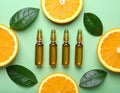 Skincare ampoules with vitamin C, slices of orange and leaves on light green bnd Royalty Free Stock Photo