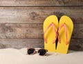 Bright flip flops and sunglasses on sand near wooden wall, space for text. Summer beach Royalty Free Stock Photo