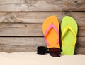 Bright flip flops and sunglasses on sand near wooden wall, space for text. Summer beach Royalty Free Stock Photo