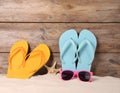Bright flip flops and sunglasses on sand near wooden wall, space for text. Summer beach Royalty Free Stock Photo