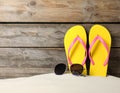 Bright flip flops and sunglasses on sand near wooden wall, space for text. Summer beach Royalty Free Stock Photo