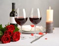 Romantic table setting with glasses of red wine, rose flowers and burning candles Royalty Free Stock Photo
