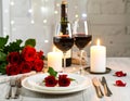 Romantic table setting with glasses of red wine, rose flowers and burning candles Royalty Free Stock Photo