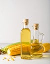 Bottle of corn oil and fresh cobs on table against light wall Royalty Free Stock Photo