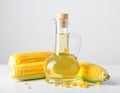 Bottle of corn oil and fresh cobs on table against light wall Royalty Free Stock Photo