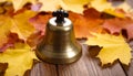 generated using AI.A small brass service bell is placed on a wooden surface surrounded by autumn leaves in shades of yellow Royalty Free Stock Photo