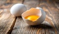 generated using AI.A cracked egg with the yolk visible sits on a rustic wooden surface, next to another intact egg. Royalty Free Stock Photo