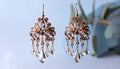 generated using AI.Ornate gold-toned chandelier earrings with intricate floral designs feature clear teardrop Royalty Free Stock Photo
