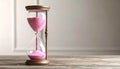 Hourglass with pink flowing sand on wooden table. Space for text Royalty Free Stock Photo