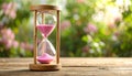 Hourglass with pink flowing sand on wooden table. Space for text Royalty Free Stock Photo