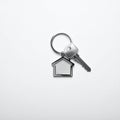 Keys with trinket in shape of house on white background, top view and space for text. Royalty Free Stock Photo