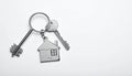 Keys with trinket in shape of house on white background, top view and space for text. Royalty Free Stock Photo