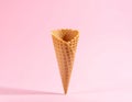 Empty wafer ice cream cone on pale pink background Royalty Free Stock Photo