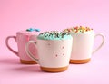 Delicious edible biscuit coffee cups decorated with sprinkles on color background Royalty Free Stock Photo