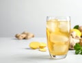Glass of tasty ginger ale with ice cube and ingredients on white table, closeup Royalty Free Stock Photo