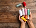 Woman holding clews of threads on wooden background, top view. Space for text Royalty Free Stock Photo