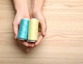 Woman holding clews of threads on wooden background, top view. Space for text Royalty Free Stock Photo