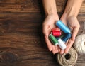 Woman holding clews of threads on wooden background, top view. Space for text Royalty Free Stock Photo