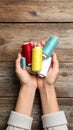 Woman holding clews of threads on wooden background, top view. Space for text Royalty Free Stock Photo