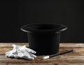 Magician\'s hat, wand and gloves on wooden table against black background Royalty Free Stock Photo