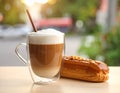 Cup of caramel macchiato and tasty pastry on table Royalty Free Stock Photo