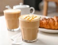 Cup of caramel macchiato and tasty pastry on table Royalty Free Stock Photo