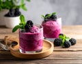 Two clear glasses on a wooden tray each contain a vibrant blackberry sorbet. Royalty Free Stock Photo