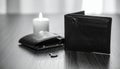 Two black leather wallets are placed on a wooden surface, with a lit candle in the background Royalty Free Stock Photo