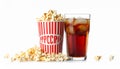 A glass filled with dark soda and ice cubes sits beside a large tub of popcorn. Royalty Free Stock Photo