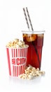 A glass filled with dark soda and ice cubes sits beside a large tub of popcorn. Royalty Free Stock Photo
