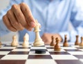 A man in a blue jacket and white shirt moves a black chess piece on a checkered board. Royalty Free Stock Photo