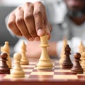 A man in a blue jacket and white shirt moves a black chess piece on a checkered board. Royalty Free Stock Photo