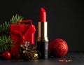 Red lipstick stands upright against a backdrop of wrapped gifts adorned with red ribbons. Royalty Free Stock Photo