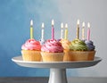 Birthday cupcakes with candles on stand against color background Royalty Free Stock Photo